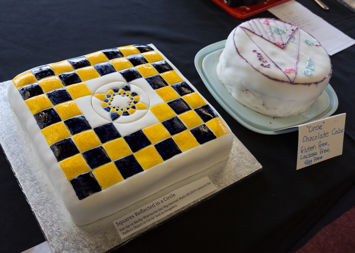 Two cakes decorated with icing. One shows a checkerboard pattern and its reflection in a circle. The other shows a geometric diagram.