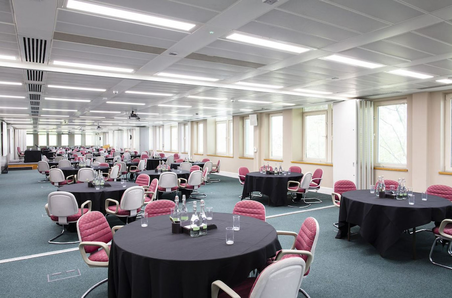 'The Meg'. A long room with round tables arranged with chairs around each table, with windows along one side of the room.